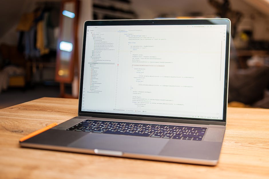 A close-up of a laptop displaying a code editing software with lines of programming code on the screen. The screen shows a text editor with syntax highlighting, line numbers, and various open tabs and